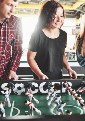 Smiling young people playing table football while indoors.