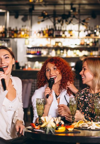 Young women in a bar singing karaoke